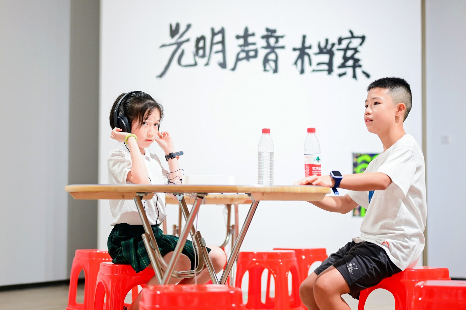 A girl listens to the folk song recordings by Huang Cheng while a boy is waiting for his turn.jpg